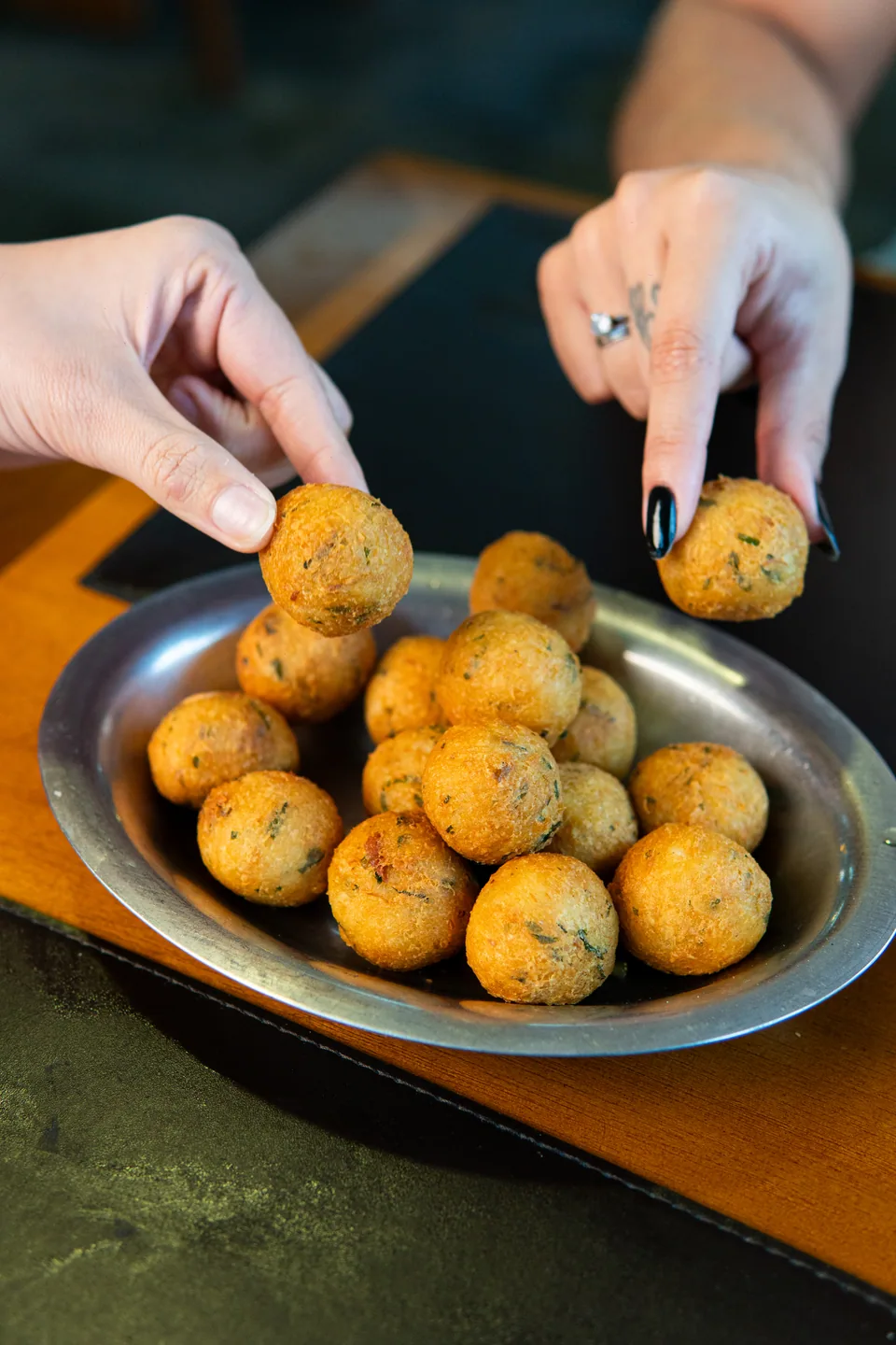 Mão pegando bolinho de bacalhau quentinho · clássico da casa